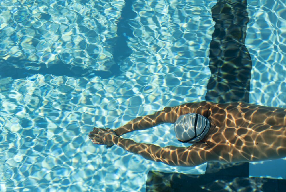 alto-angolo-del-nuotatore-maschio-che-nuota-nella-piscina-di-acqua